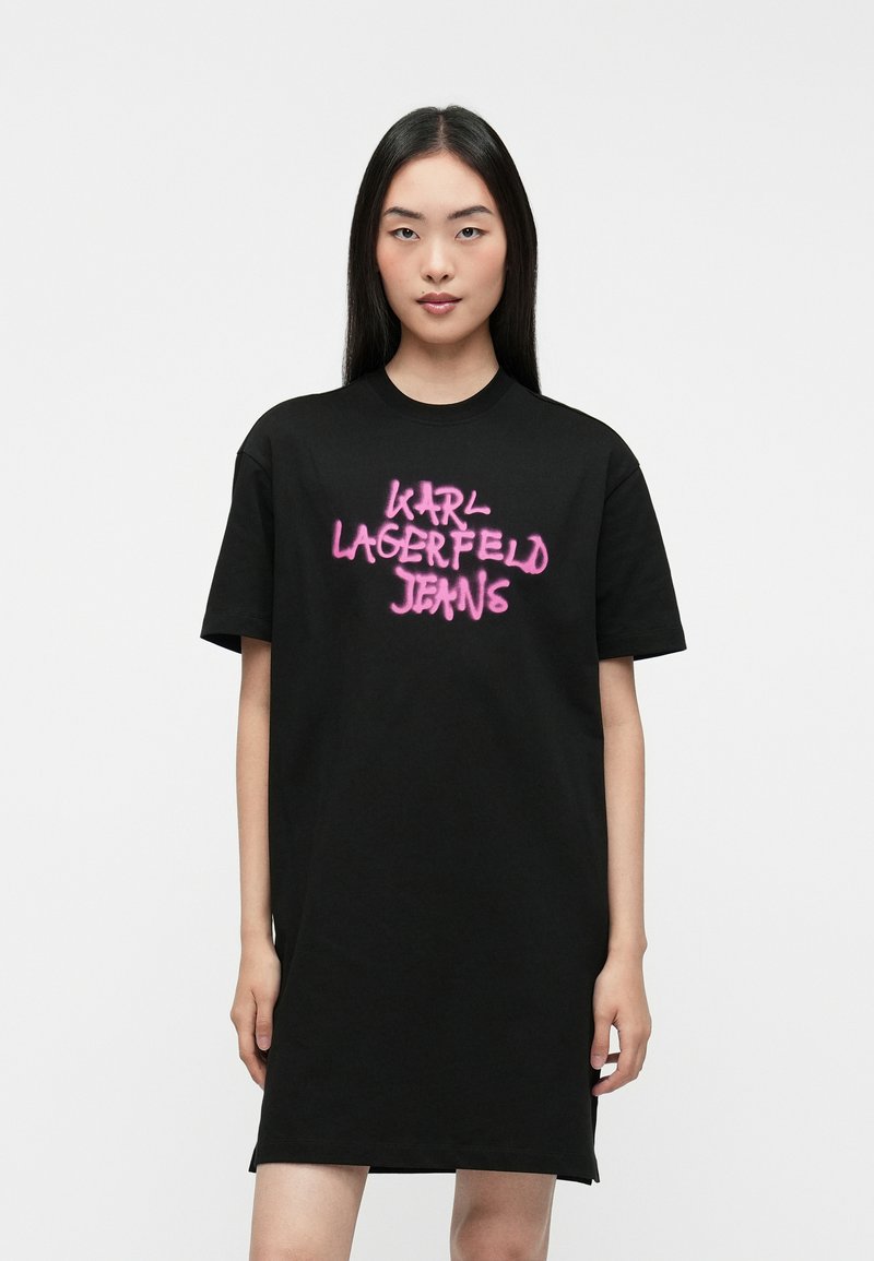 Czarna sukienka t-shirtowa wykonana z bawełny, z odważnym różowym, sprejowanym logo "KARL LAGERFELD JEANS" na przodzie. Krótkie rękawy, luźny krój.