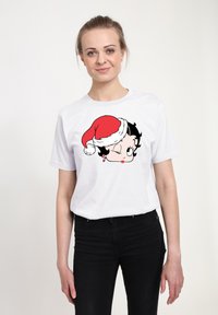 Hvid t-shirt med en tegneseriefigur med sort hår, der blinker, iført en rød og hvid julestrudse og holder en slikstok illustration.