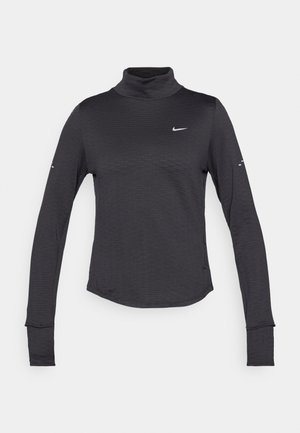 Sort langærmet turtleneck skjorte med et subtilt tekstureret mønster, der har et lille hvidt Nike-logo på brystet og tommelhuller i manchetterne.
