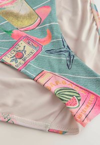 Maudymosi kostiumas su žalios spalvos raštu, vaizduojančiu gėrimų iliustracijas, ryškiomis spalvomis ir sklandžiu šviesiai kreminiu pamušalu.