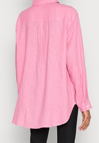 Pink long-sleeve shirt in lightweight linen, featuring a collar, a back yoke seam, drop shoulders, and buttoned cuffs. Loose-fit design.