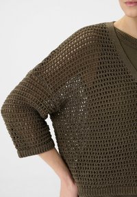 Gestrickter olivgrüner Pullover mit einer lockeren, offenen Maschenstruktur, V-Ausschnitt, verkürzten Ärmeln und gerippten Bündchen für zusätzliche Textur.