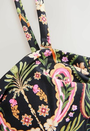 Tissu noir avec des motifs floraux et de feuilles colorés en rose, jaune et vert, avec de fines bretelles et un détail à bord festonné.