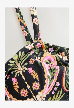 Tissu noir avec des motifs floraux et de feuilles colorés en rose, jaune et vert, avec de fines bretelles et un détail à bord festonné.