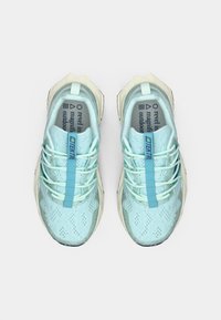 Chaussures de sport bleu clair avec une tige en mesh texturé, des lacets contrastants et une semelle extérieure en caoutchouc solide. Design unique avec un avant-pointu angulaire.
