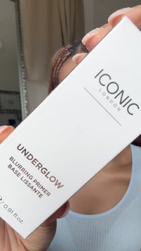 Białe opakowanie z brązowym tekstem, oznaczone "ICONIC LONDON UNDERGLOW BLURRING PRIMER". Tekst jest napisany nowoczesną, czytelną czcionką. 0,91 fl. oz.