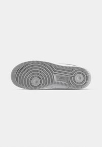 Gray Nike sneaker sole featuring a textured rubber surface with circular and wave patterns, and raised Nike logo detail.