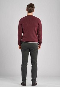 Pull en maille torsadée bordeaux avec encolure ronde, associé à un pantalon ajusté gris foncé. La tenue comprend des chaussures foncées et présente un design uni.