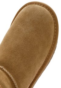 Braune Wildleder-Ankle-Boots mit abgerundetem Zehenbereich, genähten Details und einer strukturierten Gummi-Sohle. Weiches Material und nahtloses Design.
