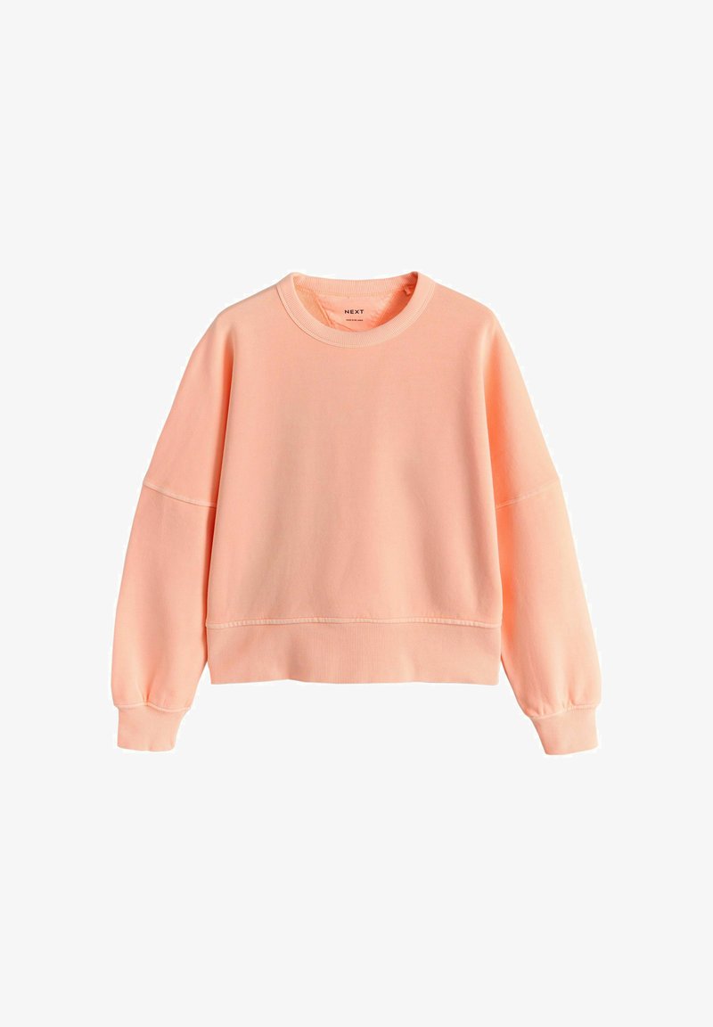 Weiches, pfirsichfarbenes Sweatshirt mit Rundhalsausschnitt, langen Ärmeln sowie gerippten Bündchen und Saum, flach auf einem weißen Hintergrund liegend.