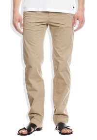 Beiga bomullschinos med smal passform och subtila vevor, matchade med svarta sandaler med öppen tå som har remmar över foten.