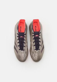 Scarpini da calcio grigi con finitura lucida, dotati di lacci e dettagli blu navy, linguetta in rete e imbottitura interna rosa con fori di ventilazione.