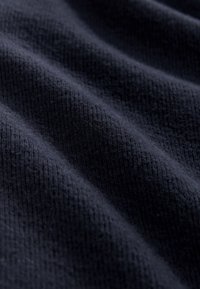 Sötét tengerészkék texturált szövet, puha, bordázott felülettel és finom fényességgel, átfedő redőkkel és sima felülettel.