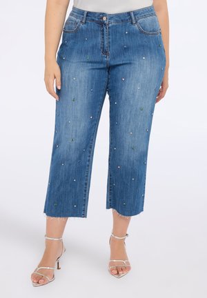 Jeans cortos azules con dobladillo deshilachado, decorados con gemas multicolores dispersas. Hechos de mezclilla, cuentan con un diseño clásico de cinco bolsillos.
