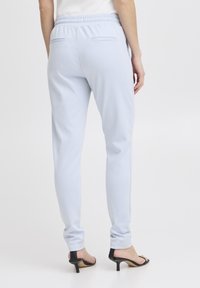 Ljust blå joggingbyxor med elastisk midjeband, slim fit och två bakfickor. Mjuk textur och slät yta.