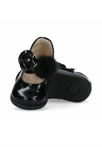 Scarpe in pelle verniciata nera con punta arrotondata, caratterizzate da un accento floreale e un dettaglio in pompon di pelliccia, fissate con una fascia a fibbia. Suola testurizzata.