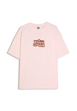 Jasnoróżowa koszulka z krótkim rękawem z brązowym napisem „Welcome to Animal Crossing” oraz ikoną zębatki nadrukowaną na środku przodu.
