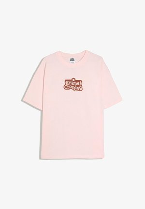 Világos rózsaszín, rövid ujjú póló, barna „Welcome to Animal Crossing“ felirattal és fogaskerék ikon nyomattal a középső elülső részen.