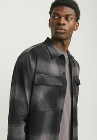 Sort og grå plaid skjorte med button-down krave, lange ærmer, to brystlommer og en glat tekstur. Subtil gradientmønster.