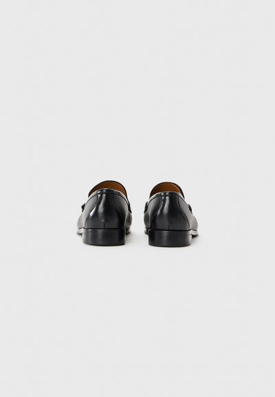 Schwarze Lederschuhe mit strukturierter Oberfläche, versehen mit einer glatten Hinterseite und einem niedrigen, langlebigen Absatz. Das Innere besteht aus braunem Leder.
