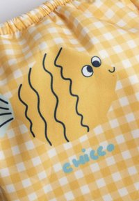 Tessuto giallo con un motivo a quadretti presenta un design di pesce cartone animato in giallo, con accenti neri e testo blu che spelling "Chicco."