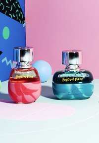 To parfymeflasker ved siden av hverandre. Venstre: rosa rund kropp, sølvhette, klar øvre del. Høyre: teal rund kropp, sølvhette, klar øvre del.