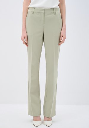 Pantaloni su misura verde pallido con una texture liscia, design a gamba dritta e due tasche frontali. Abbinati a tacchi bianchi a punta.