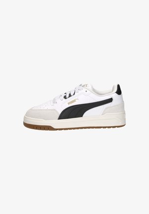 Witte en zwarte lage Puma-sneaker met gumzool, suède neus en gouden logo aan de zijkant, gezien vanaf de buitenkant.