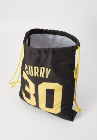 Borsa a cordoncino nera con accenti gialli, con il nome "CURRY" e il numero "30" in un grande carattere grassetto. Texture in nylon liscia.