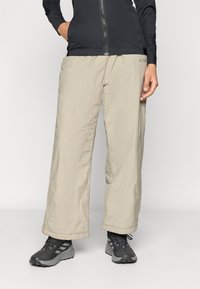 Ανοιχτόχρωμα ελαφριά παντελόνια εξωτερικού χώρου με υφή τσακισμένη, ελαστική μέση και χαλαρή εφαρμογή. Συνδυασμένα με σκούρα μποτάκια πεζοπορίας.