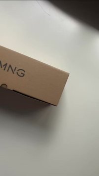 Brown cardboard box with a rectangular shape, featuring a minimalist design and embossed text. It has a small circular opening on the side.
