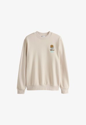 Kreminės spalvos džemperis su nerištais rankovėmis ir apačia. Dešinėje krūtinės pusėje turi siuvinėtą gėlės dizainą. Lygus audinio paviršius.