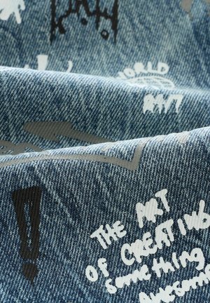 Tissu en denim avec des tons bleus, présentant des phrases imprimées en blanc et en gris ainsi que des points d'exclamation. Surface texturée avec des graphiques dispersés.