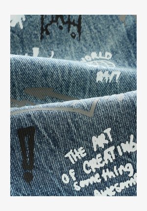 Tejido de denim en tonos azules, con frases impresas en blanco y gris y signos de exclamación. Superficie texturizada con gráficos dispersos.