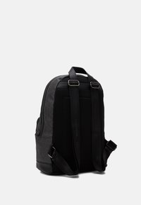 Black backpack with geometric pattern, textured mesh back, adjustable straps, and metallic hardware. Smooth lower section with logo details.