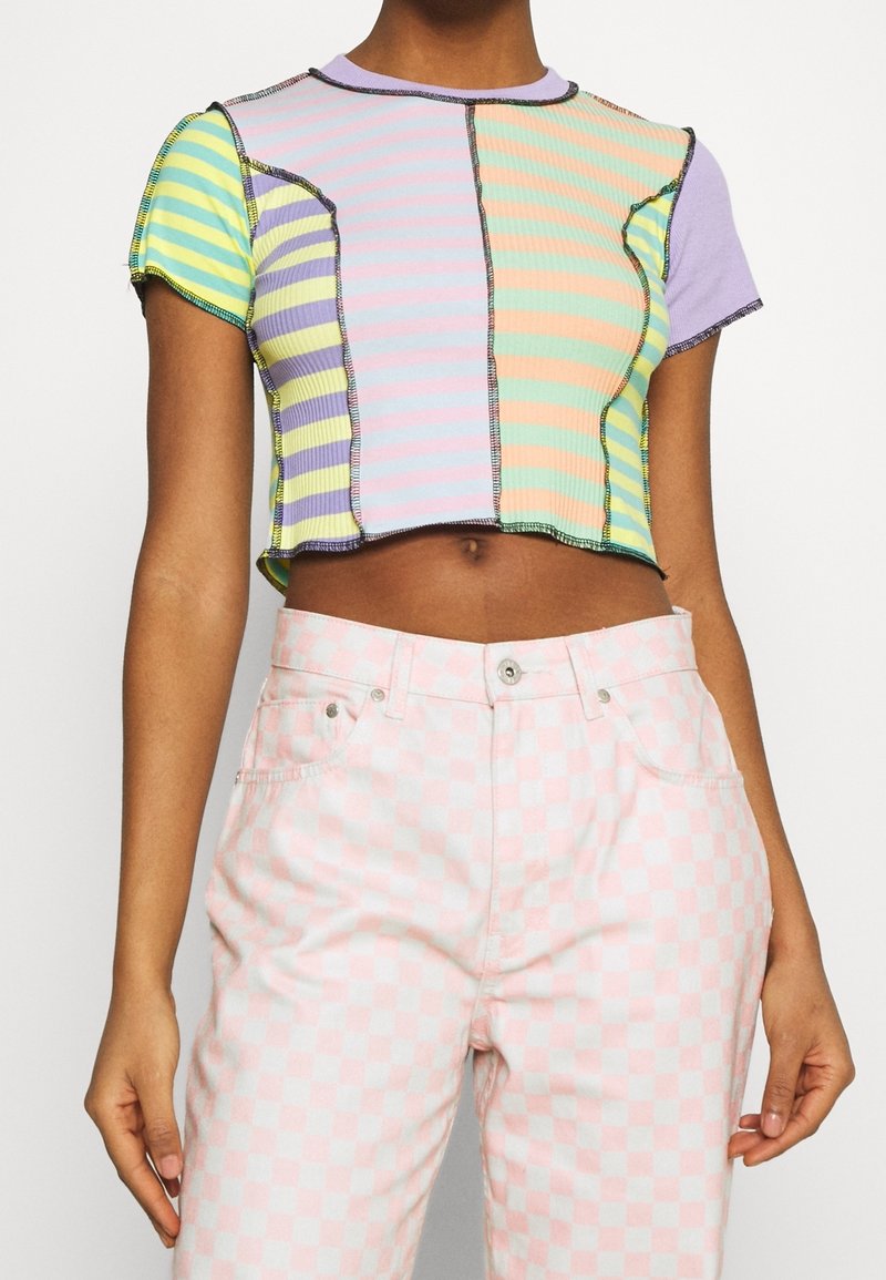 Cropped short-sleeve top featuring pastel striped panels in green, purple, yellow, and pink with black stitching details.
