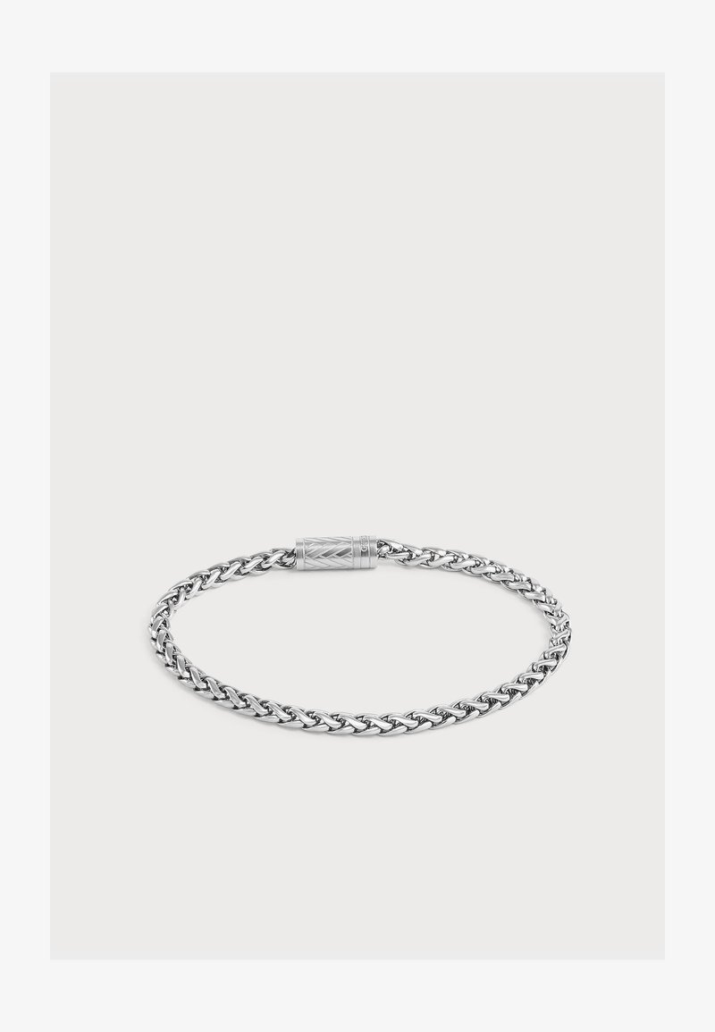 Bracelet chaîne torsadée en argent avec un fermoir cylindrique orné de motifs géométriques gravés, présenté sur un fond clair uni.