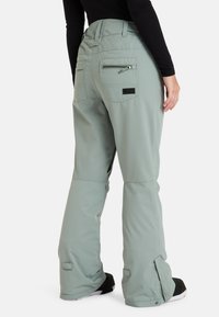 Lichtgroene sneeuwbroeken met een doorgestikte tailleband, een ritszak aan de achterkant en verstelbare manchetten. Gemaakt van duurzaam, waterafstotend materiaal.