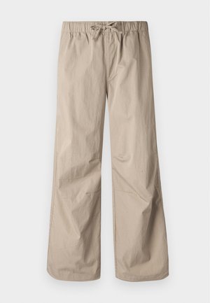 Kermanväriset leveät housut, joissa on joustava vyötärö ja naru. Sujuva tekstuuri, kaksi sivutaskua ja minimaalinen sauma rentoa istuvuutta varten.