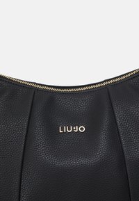 Borsa a spalla in pelle nera testurizzata con zip dorata e logo. Presenta una forma curvata e sottili pieghe vicino alla parte superiore.