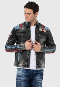 Jeansjack met vervaagde zwarte was, rode en blauwe accenten, voorkruim pockets, ribgebreide mouwen en een logo patch op de borst. Rits sluiting.
