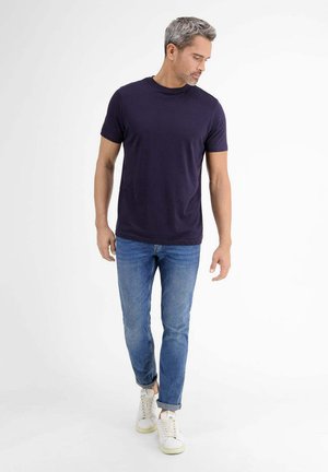 Navyblaues Baumwoll-T-Shirt, kombiniert mit hellblauen Jeans und weißen Sneakers. Das T-Shirt hat einen klassischen Rundhalsausschnitt und kurze Ärmel.