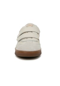 Sneaker bianco in suede con due cinturini in velcro, parte superiore testurizzata e suola in gomma marrone. Presenta un logo sulla linguetta e cuciture a contrasto.