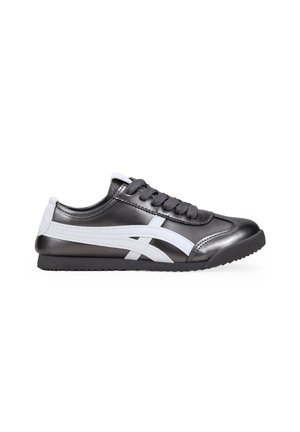 Zapatilla deportiva en blanco y negro, hecha de material sintético, con una textura suave, punta redonda, suela plana y diseño con cordones.