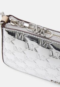 Borsa a tracolla metallica argento con motivo in rilievo del logo "MK", caratterizzata da un trim marrone e hardware argentato con chiusura a zip.