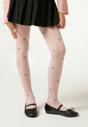 Rosa gemusterte Strumpfhosen mit kleinen schwarzen Schleifen und Punkten, aus einem weichen, dehnbaren Material, kombiniert mit schwarzen flachen Schuhen und einem faltigen Rock.