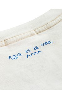 Bawełniana koszulka z okrągłym dekoltem, zdobiona niebieskim haftowanym napisem "Agua es la vida" oraz falistym detalem na kremowym tle.