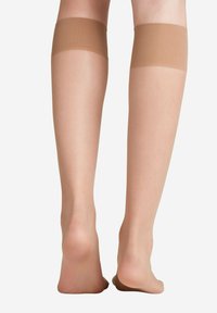 Beige bovenbeen kousen met een gladde, doorzichtige textuur en een brede, zachte band aan de bovenkant. Ontworpen voor een comfortabele pasvorm op het been.