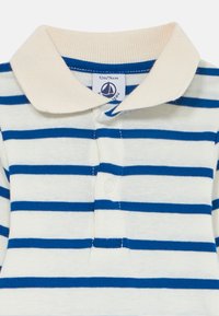 Wit en blauwe horizontaal gestreepte baby polo t-shirt met een crèmekleurige kraag en twee drukknopen aan de voorkant, maatlabel 12m/74cm zichtbaar binnenin de kraag.