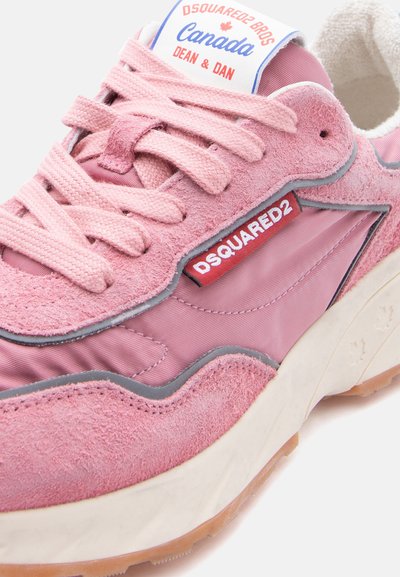 Baskets en suède et tissu rose avec lacets roses, semelle blanche, étiquette rouge "Dsquared2" et texte sur la languette disant "Dsquared2 Bros Canada Dean & Dan."